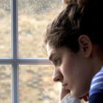 Sad/depressed young woman by rainy window
